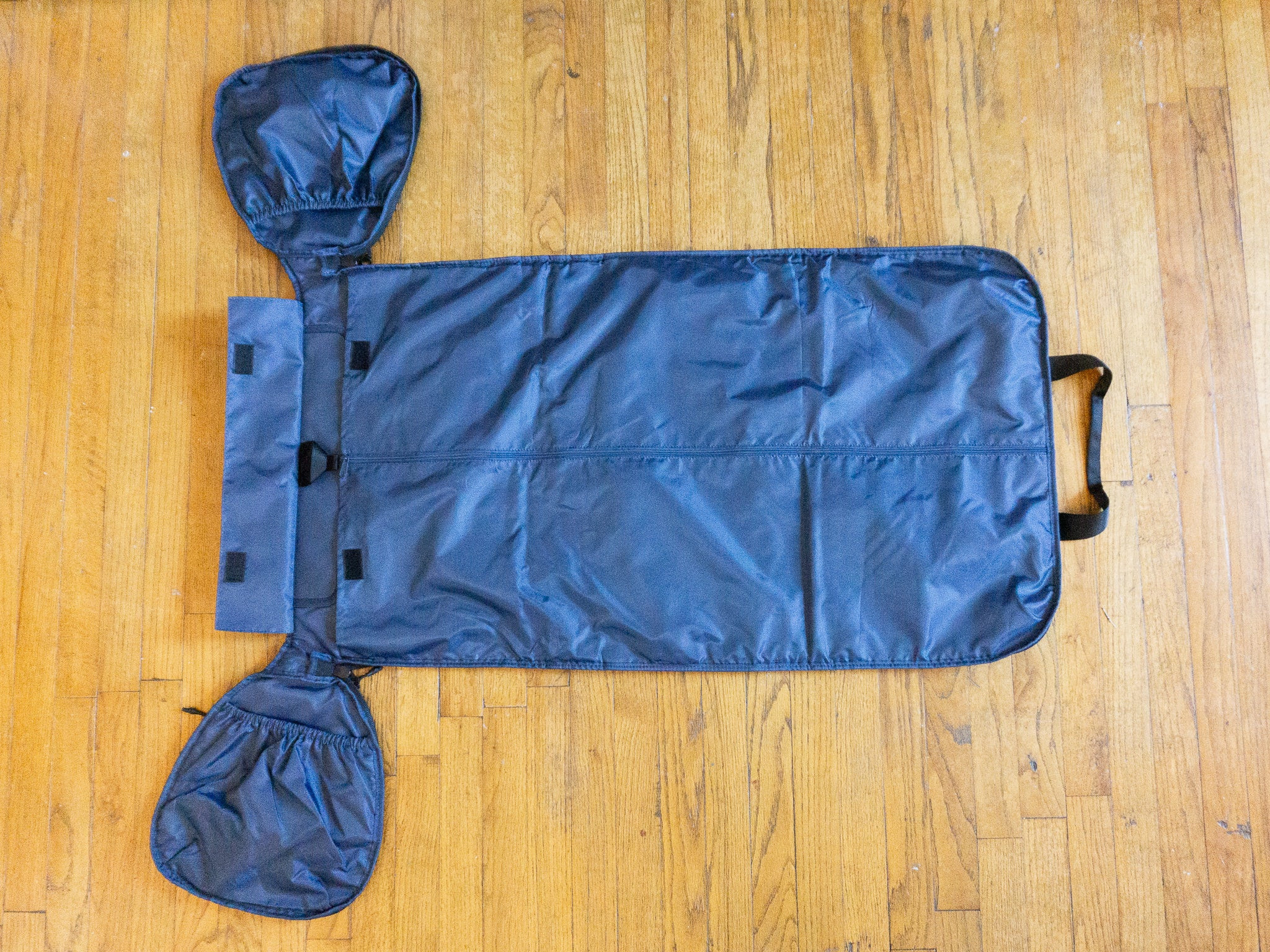 Túi Halfday Duffel được mở khóa kéo, mở ra và trải trên sàn gỗ.