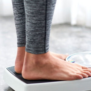 Người phụ nữ đứng trên cân sau chương trình giảm cân từ Genesis Lifestyle Medicine