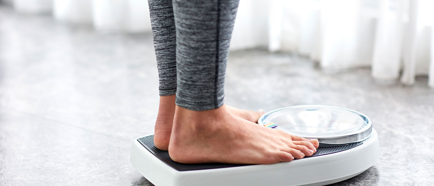 Người phụ nữ đứng trên cân sau chương trình giảm cân từ Genesis Lifestyle Medicine