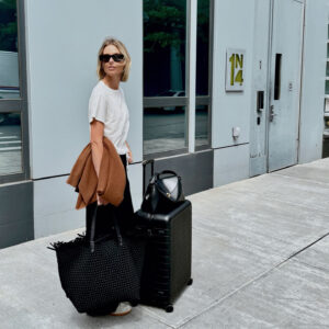 Natalie Cantell diện trang phục trung tính đi du lịch với kính râm Celine, quần Vuori, áo len cashmere Nordstrom, áo phông H&M, giày Adidas Sambas, túi Toteme T-Lock, túi Naghedi oversize và vali Away.