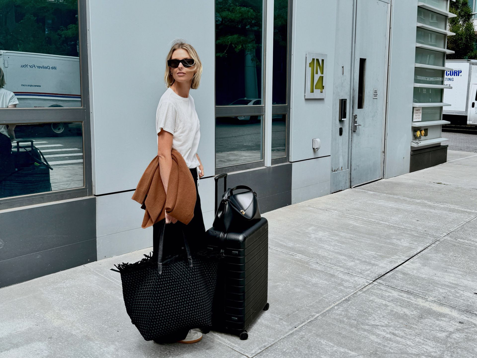 Natalie Cantell diện trang phục trung tính đi du lịch với kính râm Celine, quần Vuori, áo len cashmere Nordstrom, áo phông H&M, giày Adidas Sambas, túi Toteme T-Lock, túi Naghedi oversize và vali Away.