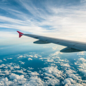 Máy bay bay trên bầu trời xanh với những đám mây trắng, minh họa cho việc onward travel bằng đường hàng không
