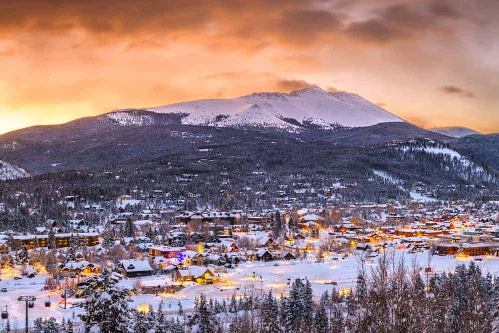 Thị trấn Breckenridge, Colorado phủ đầy tuyết trắng, với những ngôi nhà gỗ ấm cúng và những ngọn núi hùng vĩ phía sau.