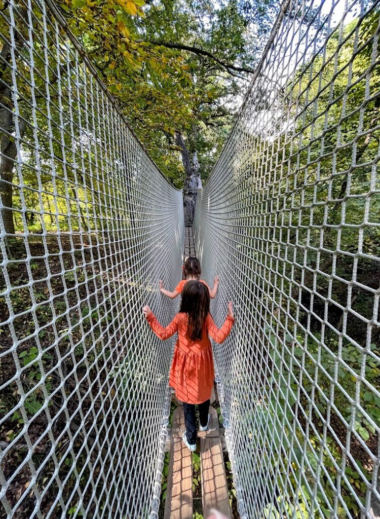 Các cô gái chạy dọc theo một cây cầu dây tại Arbor Day Farm Treetop Adventure, Nebraska City, Nebraska