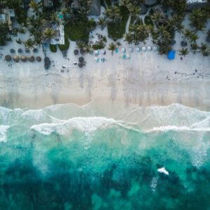 Toàn cảnh bãi biển cát trắng nguyên sơ và làn nước màu ngọc lam của Tulum, với hàng cọ và khu nghỉ dưỡng sang trọng bên bờ biển—hoàn hảo cho một chuyến đi chơi sinh nhật lần thứ 30.