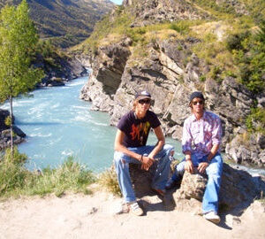 Tom và bạn của anh ấy ở New Zealand năm 2005, ngồi trên những tảng đá trước một dòng sông